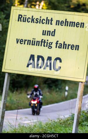 Horben, Deutschland. September 2020. Ein Schild des ADAC (Allgemeiner Deutscher Automobil Club) mit der Aufschrift "Rücksicht nehmen und künftig fahren ADAC" befindet sich an der Landstraße L124 bei Horben im Schwarzwald, während im Hintergrund ein Motorradfahrer zu sehen ist. Die Straße, auch Schauinslandstraße genannt, ist besonders bei Motorradfahrern am Abend und am Wochenende beliebt. Bis 1984 war die Straße auch Austragungsort des ADAC Schauinsland-Rennens, das von Horben zum Schauinsland-Pass führte. Quelle: Philipp von Ditfurth/dpa/Alamy Live News Stockfoto
