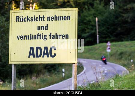 Horben, Deutschland. September 2020. Ein Schild des ADAC (Allgemeiner Deutscher Automobil Club) mit der Aufschrift "Rücksicht nehmen und künftig fahren ADAC" befindet sich an der Landstraße L124 bei Horben im Schwarzwald, während im Hintergrund ein Motorradfahrer zu sehen ist. Die Straße, auch Schauinslandstraße genannt, ist besonders bei Motorradfahrern am Abend und am Wochenende beliebt. Bis 1984 war die Straße auch Austragungsort des ADAC Schauinsland-Rennens, das von Horben zum Schauinsland-Pass führte. Quelle: Philipp von Ditfurth/dpa/Alamy Live News Stockfoto
