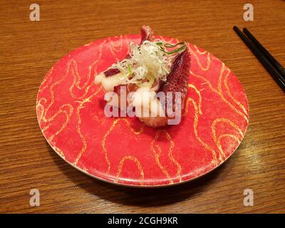 Sushi mit Tintenfisch-Bein und dünnen Scheiben Frühlingszwiebeln gekrönt. Beliebtes Sushi-Restaurant mit Förderband in Seoul. Stockfoto