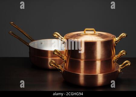 Glänzendes Vintage Kupfer Kochgeschirr auf dunklem Hintergrund Stockfoto
