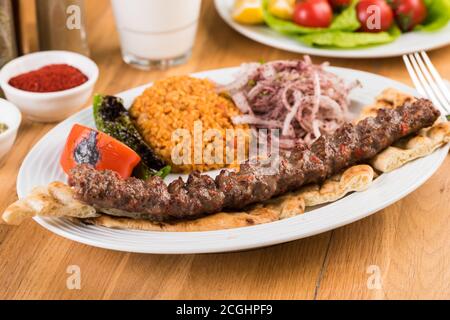 Türkischer Adana Kebab mit Gemüse auf Holztisch Stockfoto