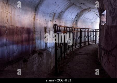 Ein Metallzaun, der in den unterirdischen Teil der Festung bei Fort Pospelov auf der russischen Insel in Wladiwostok absteigt. Stockfoto