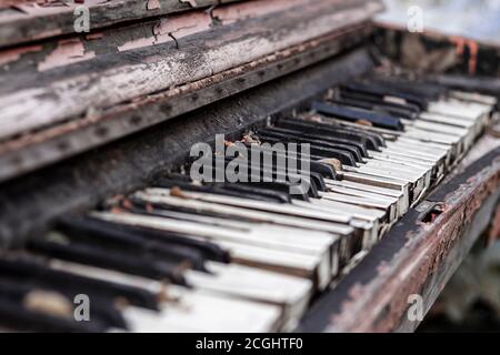 Altes gebrochenes rotes Klavier mit geschälter Farbe von Regen und Wind, draußen an einem Herbsttag. Unnötiges Musikinstrument entsorgt. Stockfoto