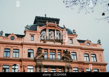 Prague, Czechia - EIN schrulliges, pinkfarbenes Gebäude in der Nähe des Nationalmuseums und mit Engelsstatuen im Eingang. Stockfoto