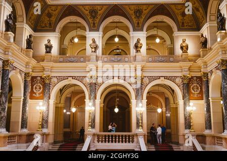 Prag, Tschechien - das Innere des Nationalmuseums und seine Haupthalle mit der vorherrschenden Verwendung von Gold zu braunen Farben und einige Touristen versammelt. Stockfoto
