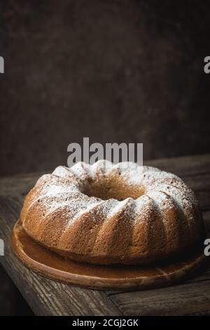 Landhausstil Apple Bundt Cake bestreut mit Puderzucker auf alten Holztisch Stockfoto
