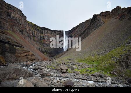 Hengifoss Wasserfall im Nordosten Islands. Die horizontalen roten Tonschichten sind im vulkanischen Basaltgestein zu sehen, das die Wasserfälle umgibt Stockfoto