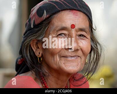 Lächelnde, alte nepalesische Hindu-Frau mit rotem Bindi auf der Stirn posiert für die Kamera. Stockfoto