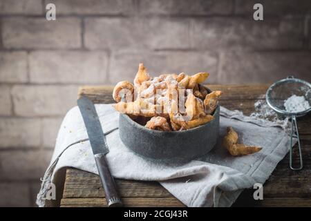 Reisig - russische traditionelle Plätzchen mit Puderzucker. Mit hvorost auf hölzernen Tischplatte Stockfoto