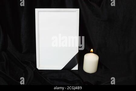 Kondolenzkarte. Gedenkrahmen mit schwarzem Band. Weiße Kerze. Schwarzer Hintergrund. Stockfoto