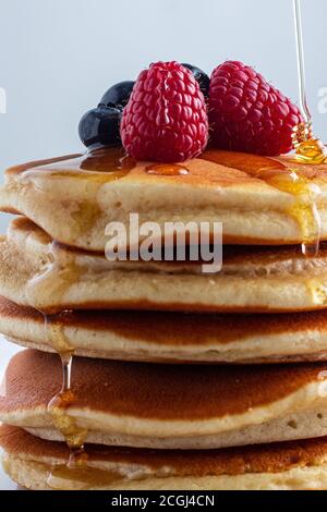 Flauschiger Pfannkuchen mit Himbeeren und Heidelbeeren und Honig Nieselregen Stockfoto