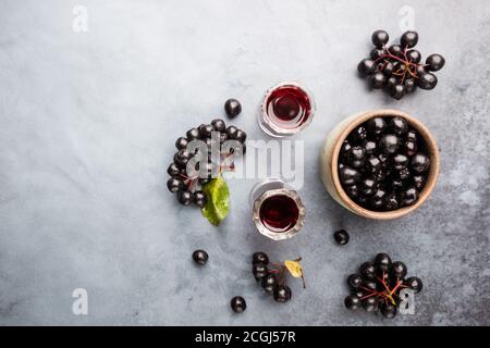 Hausgemachte schwarze Apfelbeere Wein oder Likör mit reifen Beeren, Ansicht von oben Stockfoto