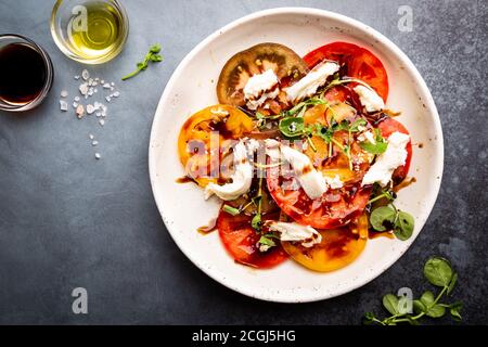 Bunter Salat mit frischen Tomaten, Mozzarella und Balsamico Essig auf einer Platte, Ansicht von oben Stockfoto