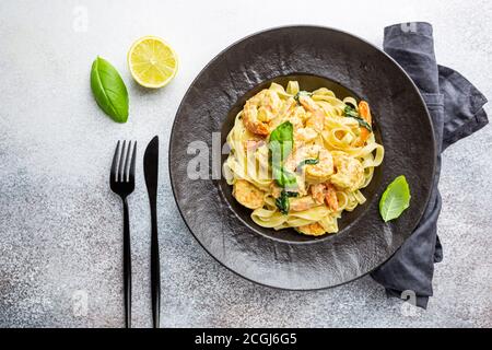 Italienische Pasta fettuccine in eine cremige Soße mit Garnelen auf einer schwarzen Platte, Ansicht von oben Stockfoto