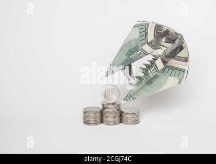Eine Origami-Figur von Dollar in Form eines Tierkopfes mit Zähnen und einer Rubel-Münze. Das Konzept des Wachstums des Dollars gegenüber dem Rubel. Stockfoto