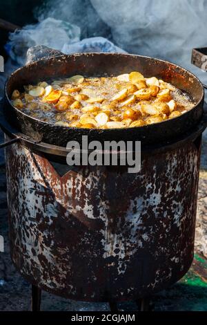 Bratkartoffeln Kochen in gusseiserner Pfanne im Freien. Street Fast Food Stockfoto