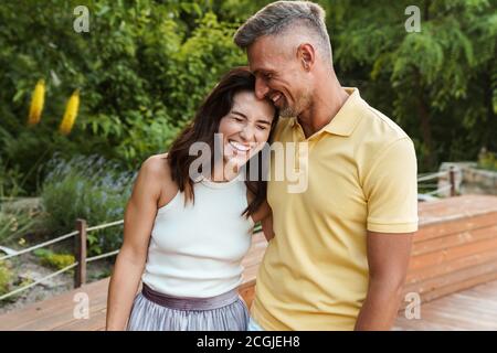 Portrait von freudiger im mittleren Alter Paar Mann und Frau lachend und Umarmen beim Gehen im Sommer Park Stockfoto