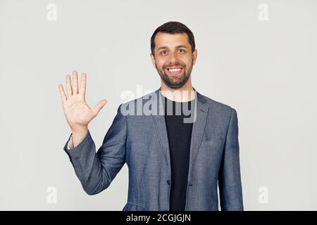 Junger Geschäftsmann Mann mit Bart lächelnd, zeigt die Nummer fünf mit den Fingern auf der Hand, lächelt selbstbewusst und glücklich, Blick in die Kamera. Der Mann zeigt fünf Finger. Nummer 5. Stockfoto