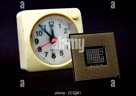 Der Computer-Prozessor auf einem dunklen Hintergrund und Vintage-Uhr. Stockfoto