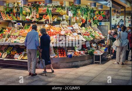 Menschen, die Maske tragen und in einem Obst- und Gemüsestände im Markt Mercado de la Encarnación einkaufen Stockfoto