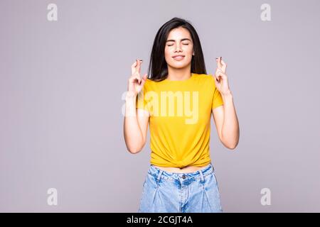 Innen- schuss von froh, glücklich, blonde Frau trägt Pullover, lächelt breit, hält die Finger gekreuzt, hofft auf gutes Glück, gegen den grauen Hintergrund Witz isoliert Stockfoto