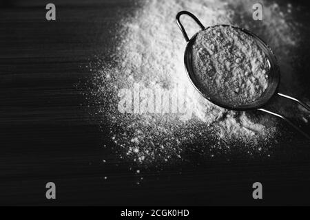 Schwarz-Weiß-Foto von Mehl im Sieb verstreut auf Ein Holzbrett Stockfoto