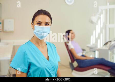 Frau Arzt Zahnarzt in medizinischen Uniform und Maske stehen und Blick auf die Kamera in der Klinik Stockfoto