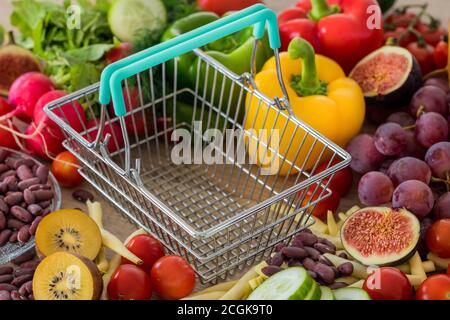 Leerer Warenkorb. Viel Essen, Gemüse und Obst in der Umgebung. Das Konzept von steigenden Preisen, Inflation und teureren Lebensmitteln Stockfoto