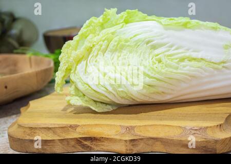 Frischer Chinakohl liegt auf einem hölzernen Schneidebrett. Zutat zum Kochen Stockfoto