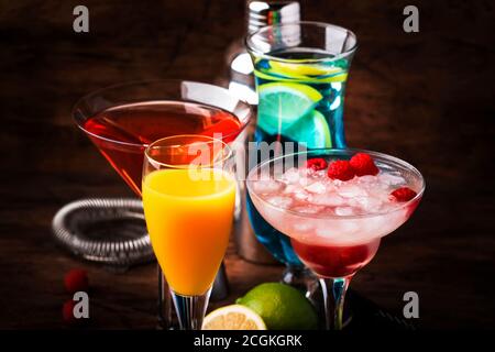 Farbenfrohe Sommercocktails. Kalte alkoholische Getränke und Getränke: mimosa, Cosmopolitan, Himbeere margarita und blau hawaii auf Holztisch Hintergrund w Stockfoto