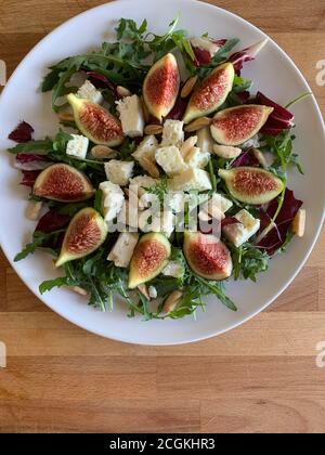 Gesunde Ernährung Konzept. Frischer Salat mit Käse, Feigen, Rucola und Mandeln. Draufsicht. Stockfoto