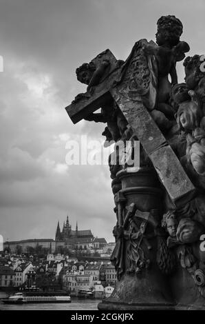 Engelstatuen mit einem religiösen Kreuz und der Kathedrale im Hintergrund, Prag, Tschechische Republik Stockfoto