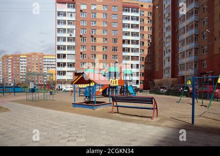 Kinderspielplatz im Hof vor einem mehrstöckigen Wohnhaus in der Stadt in der Stadt Krasnojarsk, Region Krasnojarsk, Russland Stockfoto