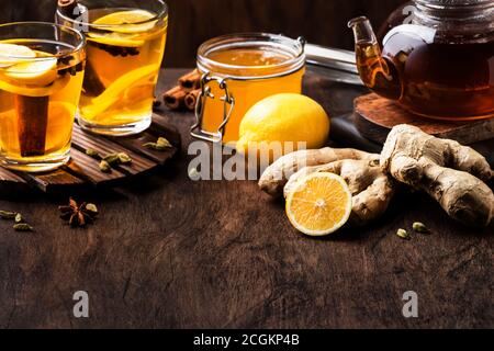 Winter oder Herbst heißen Heiltee mit Ingwer, Honig, Zitrone und Gewürzen in Glas Tasse mit Dampf, rustikalen Holzhintergrund Stockfoto