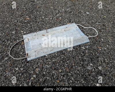 Eine gebrauchte OP-Maske auf einem Bürgersteig in der Schweiz gedumpt. Die Maske wird verwendet, um die Coronavirus-Pandemie zu bekämpfen Stockfoto