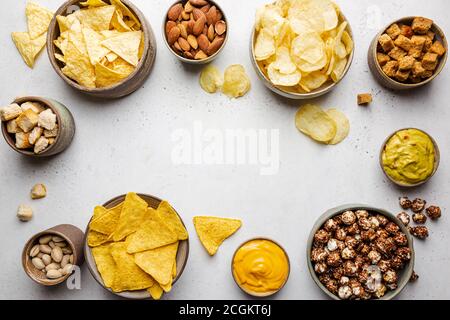 Veraity Schüsseln mit Biersnacks und Soßen auf Steintisch. Nüsse, Chips, Nachos, Cracker. Draufsicht mit Copyspace Stockfoto