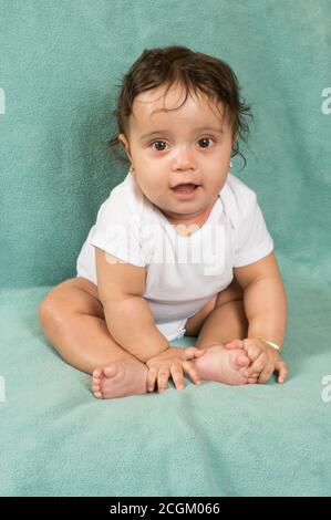 6 Monate alt Baby Mädchen sitzend Blick auf die Kamera Stockfoto