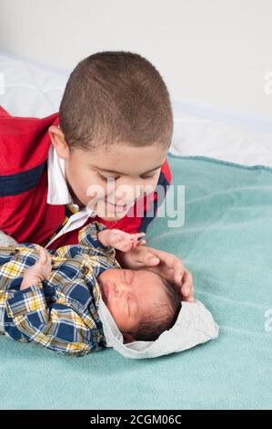 Neugeborener Junge, 1 Woche alt, bewundert von 6 Jahre altem Bruder, der sanft seinen Kopf berührt, während er schläft Stockfoto