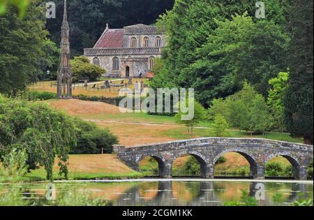 St. Peter's Church, das Bristol High Cross und die Palladian Bridge von der anderen Seite des Sees auf dem Stourhead Estate, in der Nähe von Mere, Wiltshire, England Stockfoto