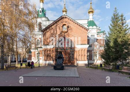 Die Pfarrei des Tempels des Heiligen Johannes des Vorläufers (1890) mit einem Denkmal für St. Luka Voyno-Jasenetsky vor ihm im Park. Stockfoto