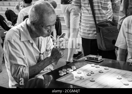 Chinatown, Singapore - 11 2018: Alter Mann spielt Xiangqi, chinesisches Schach Stockfoto