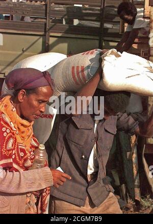 1993 - Gerade auf Schuß eines somalischen Mann, der einen 50 kg Sack Mais über seinen Kopf. Er trägt es für eine somalische Frau, die in den Frame links ist. Das Essen wird von der irischen Hilfsorganisation Sorge verteilt. Die Lebensmittel und Vorräte sind in der direkten Unterstützung der Operation Restore Hope. Stockfoto