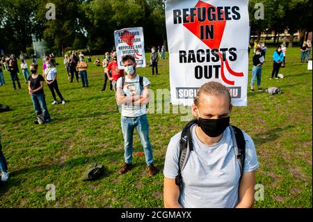 Zwei Männer tragen Gesichtsmasken und tragen während der Demonstration Plakate für Pro-Flüchtlinge auf dem Rücken.Nachdem ein Brand Griechenlands größtes Flüchtlingslager zerstört hatte und fast 13,000 Menschen keinen Schutz mehr hatten, versammelten sich Hunderte von Menschen, um die niederländische Regierung und die EU zu fordern, sich dieser Situation zu widmen. Unterstützen Sie ihre Kolleginnen und Kollegen und nehmen Sie auch eine zusätzliche Anzahl von Flüchtlingen auf. Stockfoto