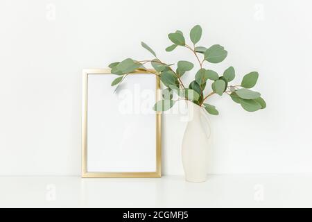 Blanker Rahmen Mockup mit einem Zweige von Eukalyptus in Vase auf Tisch auf hellem Hintergrund. Inneneinrichtung. Blog, Website oder Social Media Konzept. Stockfoto