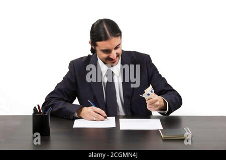 Gieriger, ehrgeiziger Mann, der an seinem Schreibtisch arbeitet Stockfoto