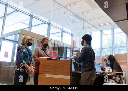 Seattle, Washington, USA. 11. August 2020 . Die Mitarbeiter am Eintrittsschalter checken die Besucher bei der Wiedereröffnung des Seattle Art Museum sorgfältig ein. Das Wahrzeichen-Museum ist seit März geschlossen, um die Ausbreitung des COVID-19-Virus zu begrenzen. Quelle: Paul Christian Gordon/Alamy Live News Stockfoto