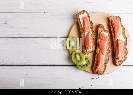 Sandwiches mit geräuchertem Lachs und Butter auf weißem Holzhintergrund. Draufsicht, Kopierraum. Stockfoto
