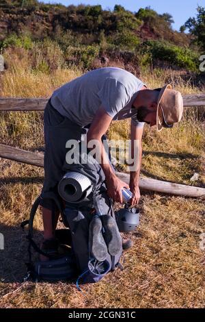 Junger hispanischer Mann in sportlicher Kleidung, der seinen Rucksack überprüft Stockfoto
