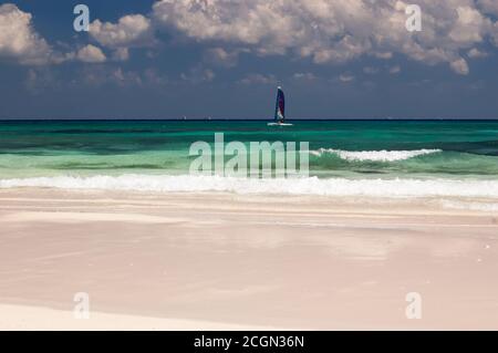 Ein Tourist segelt vor einem karibischen Strand in den Tropen. Im Hintergrund der blaue Himmel und weiße Wolken. Mexikanische Karibik Stockfoto