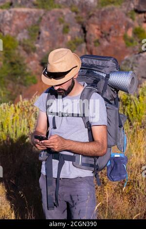 Hispanischer männlicher Trekker mit Sonnenbrille, der sein Smartphone überprüft Stockfoto